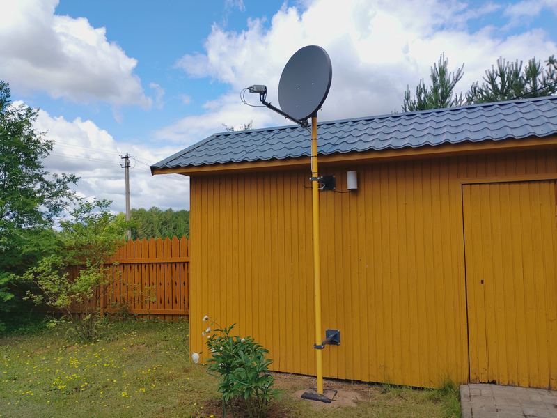 Спутниковая тарелка на мачте у постройки